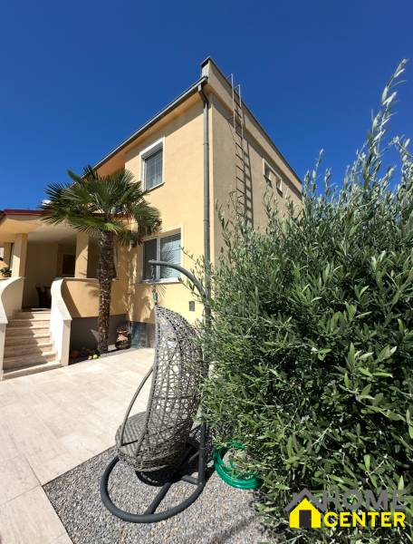 Családi ház Komáromban terasszal, kerti székkel és pálmafával az udvaron.