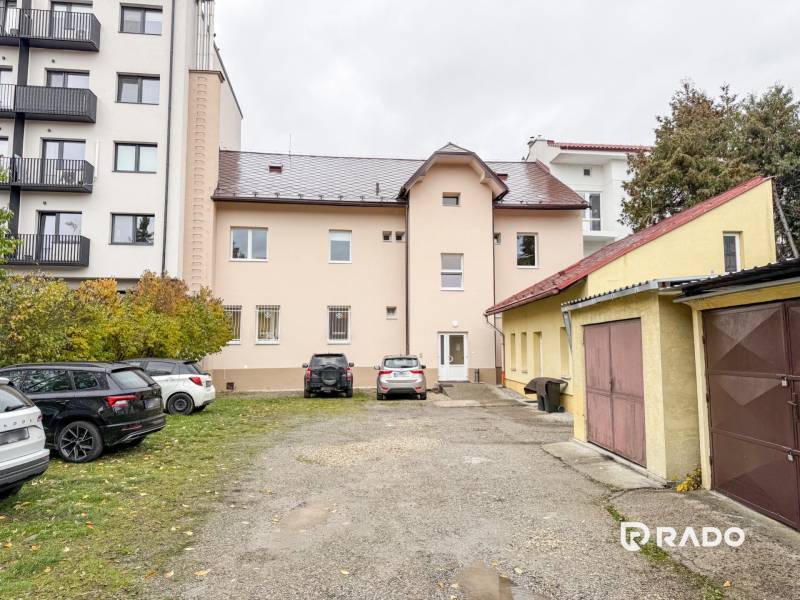 Épület a Zsolnai Pozsonyi utcában, autókkal és garázsokkal körülvéve, irodáknak alkalmas.