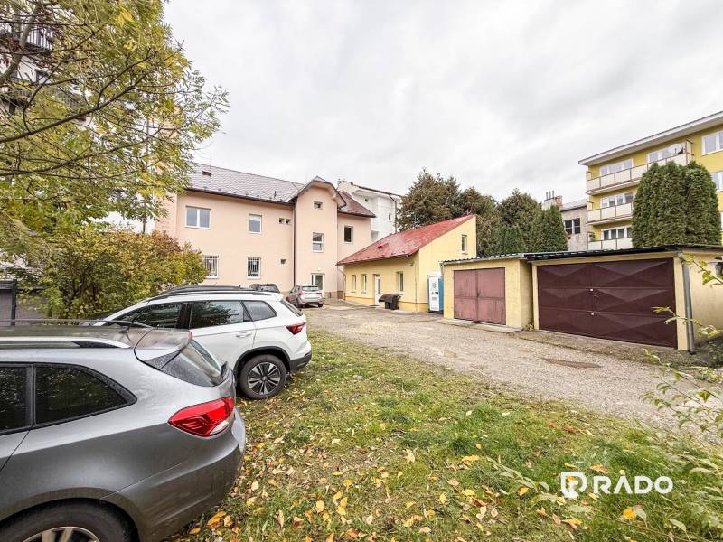 Irodák parkolója a Pozsonyi utcán, Zsolnán, autók és garázsok a háttérben.