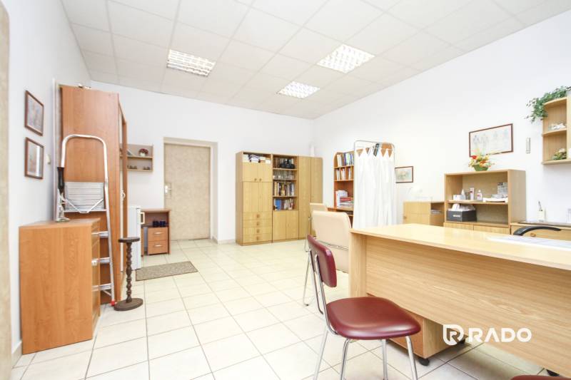 Irodák fehér falakkal, fa bútorokkal és kerámia padlóval.