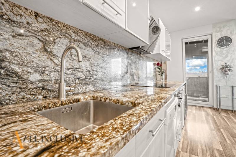 Konyha kő munkalappal és fa dekorációjú padlóval egy háromszobás lakásban.