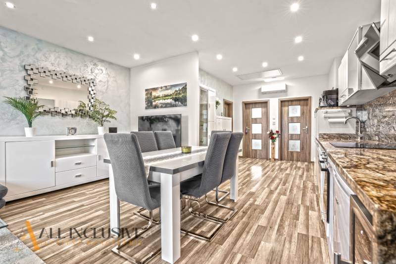 Étkező sarok egy háromszobás lakásban, fa dekoros padlóval és stílusos tükörrel.