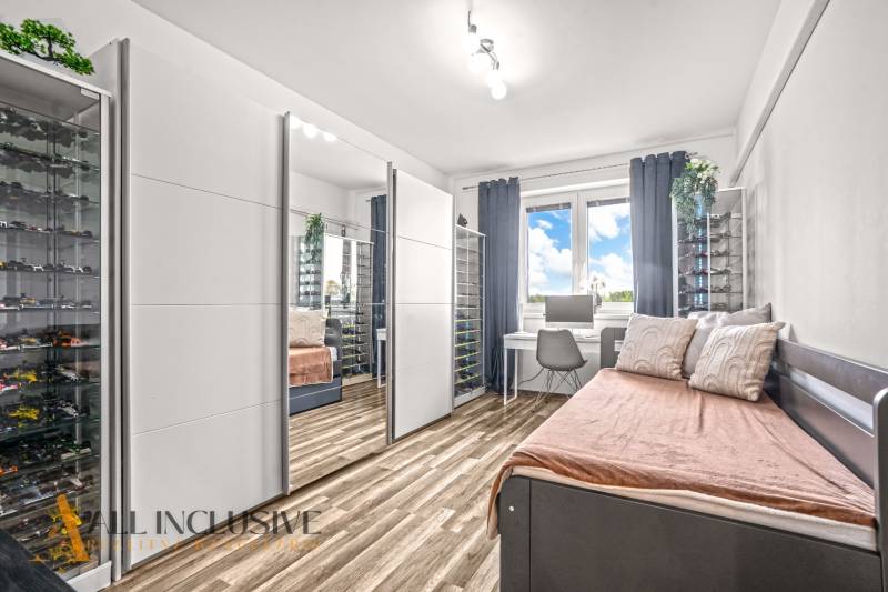 Szoba tükrös szekrénnyel, íróasztallal és fa dekorációjú padlóval egy háromszobás lakásban.