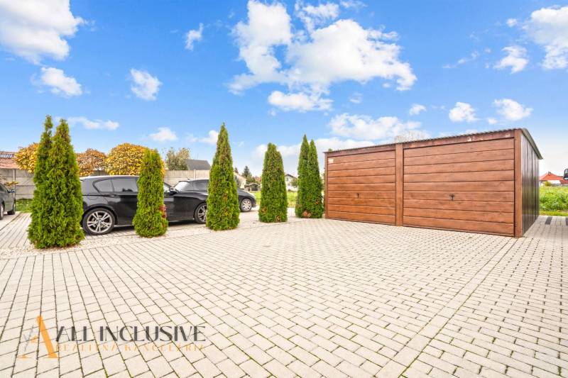 Parkolóhely egy háromszobás lakásnál Gabčíkovo-ban, autókkal és fa garázzsal.