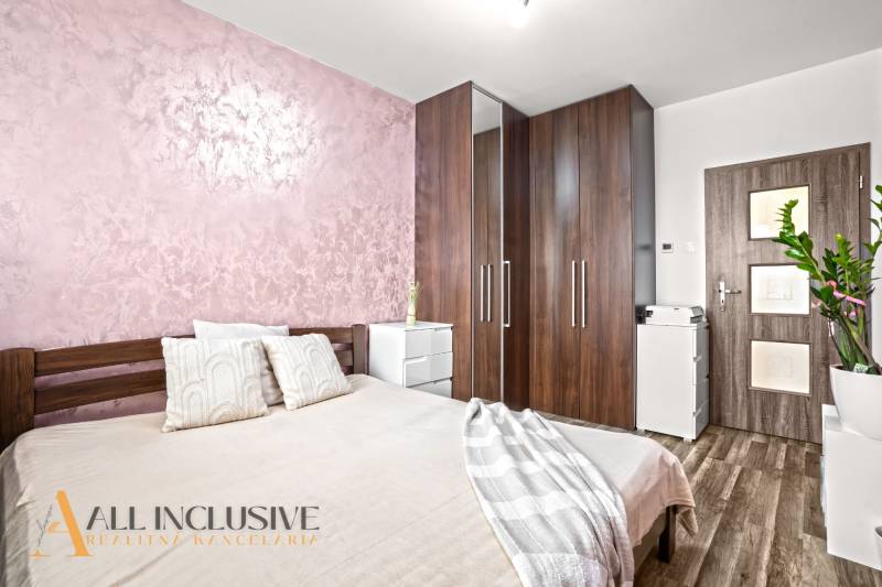 Hálószoba ággyal, szekrénnyel és fa dekorációjú padlóval egy háromszobás lakásban.