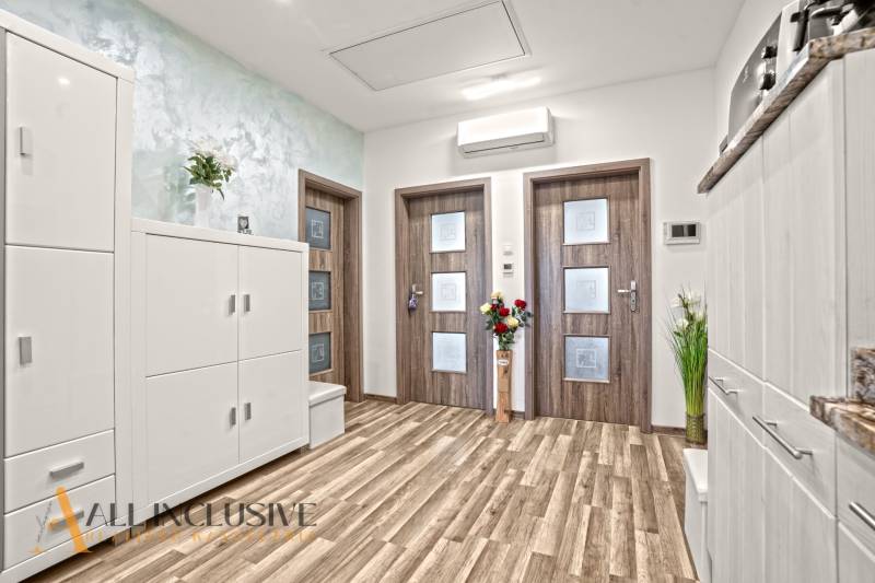 3 szobás lakás belső tere fa dekorációjú padlóval és fehér bútorokkal.