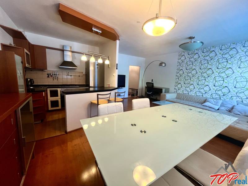 Konyha és nappali egy 3 szobás lakásban modern bútorokkal és dekoratív fallal.