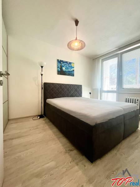 Hálószoba franciaággyal, festménnyel és állólámpával egy háromszobás lakásban.