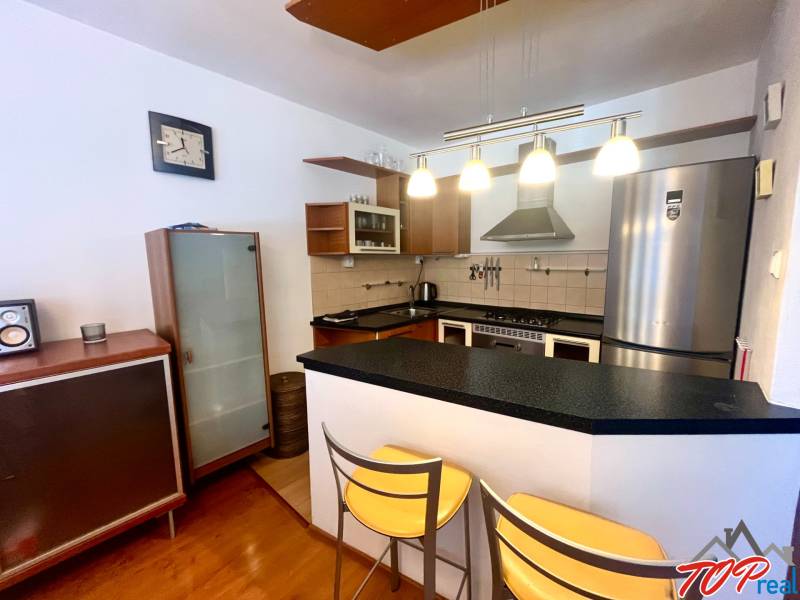 Konyha egy háromszobás lakásban bárpulttal, fém székekkel és elegáns lámpákkal.