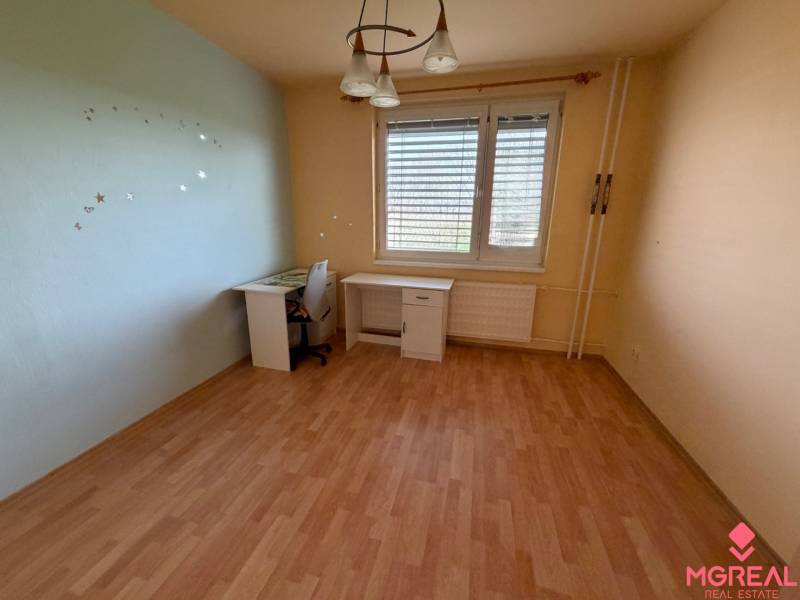 Szoba egy háromszobás lakásban fa dekor padlóval és íróasztallal.