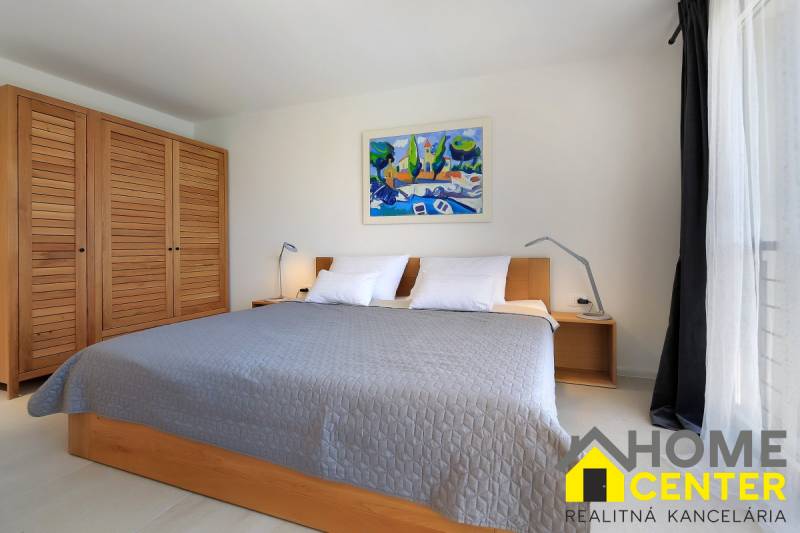 Hálószoba a villában nagy ággyal, fa szekrénnyel és képpel a falon.