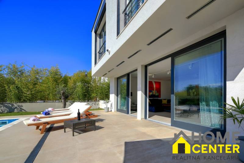 Villa Balin terasszal, napozóágyakkal, asztallal és medencével, amelyet zöld növényzet vesz körül.