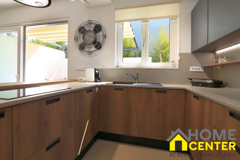 Konyha a villában nagy ablakkal, fa szekrényekkel és fa dekorációjú padlóval.