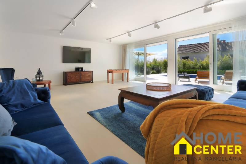 Nappali egy villában sötétkék bútorokkal, TV-vel és nagy ablakokkal.