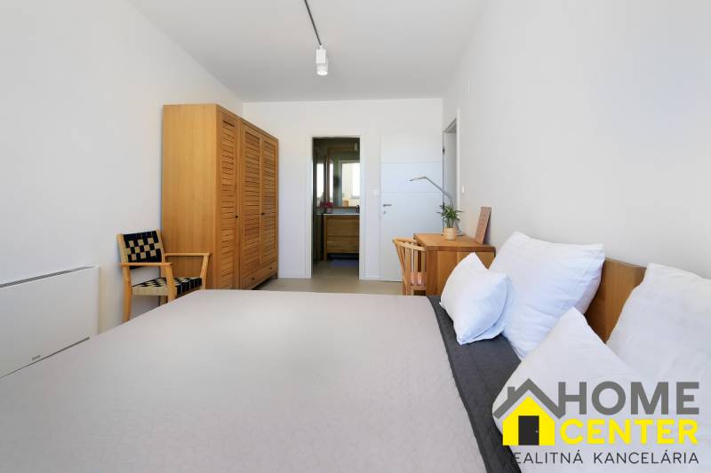 Hálószoba a villában fa bútorokkal, asztallal, székkel és kilátással a fürdőszobára.