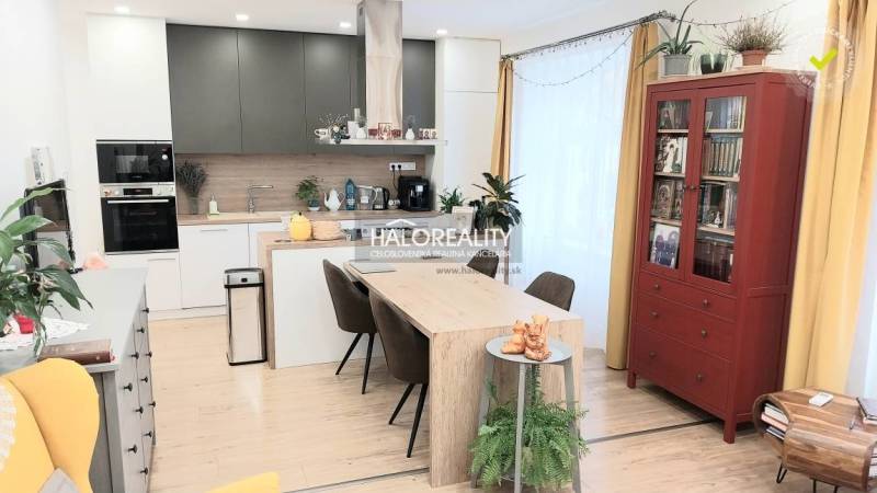 3 szobás lakás konyhájának belső tere étkezőasztallal és fa dekorációjú padlóval.