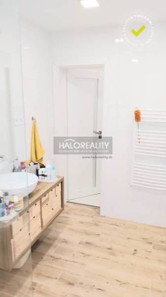 Fürdőszoba fa dekor padlóval, pultos mosdóval és fehér falakkal egy háromszobás lakásban.