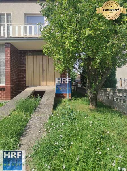 Családi ház a Radošovce-i Vieska utcában, gyep és fa a bejárat előtt.