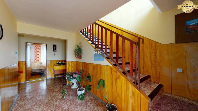 Folyosó faburkolattal, lépcsővel és szobanövényekkel egy családi házban.