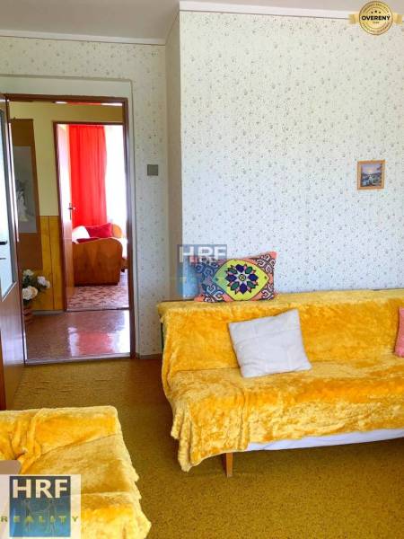 Nappali egy családi házban színes takarókkal és párnázott ülőgarnitúrával.