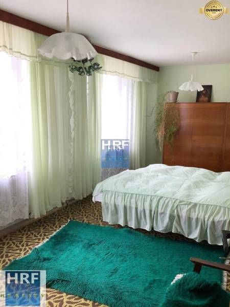 Hálószoba családi házban szőnyegekkel, függönyökkel és fa szekrénnyel.