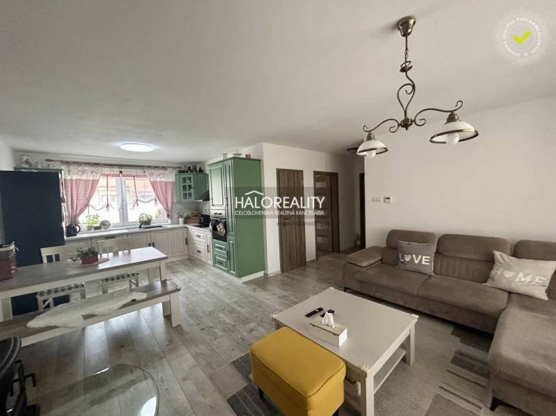 Nappali családi házban kanapéval, asztallal és konyhabútorral.