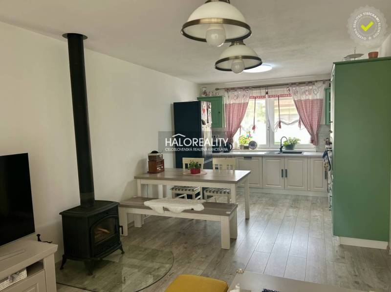 Családi ház belső tere konyhával, étkezőasztallal és cserépkályhával.