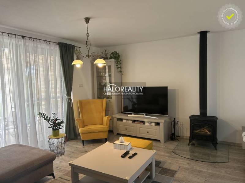 Nappali egy családi házban kandallóval, sárga fotellel és televízióval.