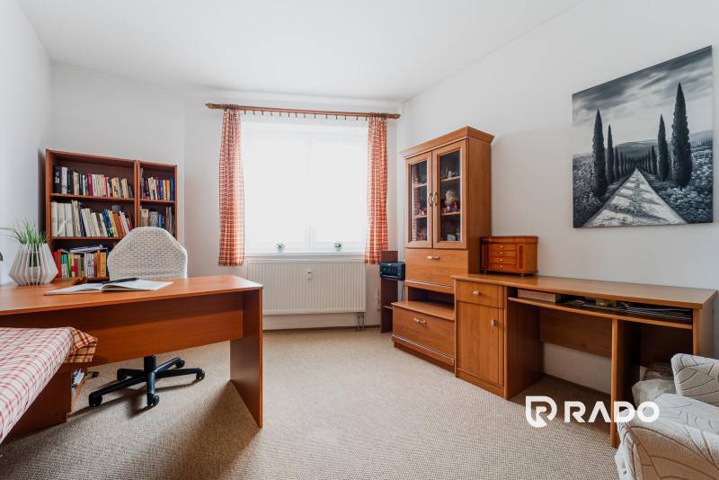 Dolgozószoba könyvtárral egy háromszobás lakásban, fa dekorációval a bútorokon.