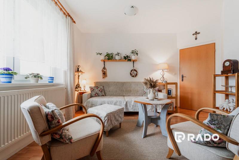 Nappali dekorációkkal, fa mintázatú padlóval és kényelmes ülőgarnitúrával egy háromszobás lakásban.