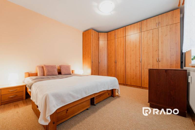 Hálószoba egy háromszobás lakásban ággyal, beépített szekrénnyel és fa dekorációjú padlóval.