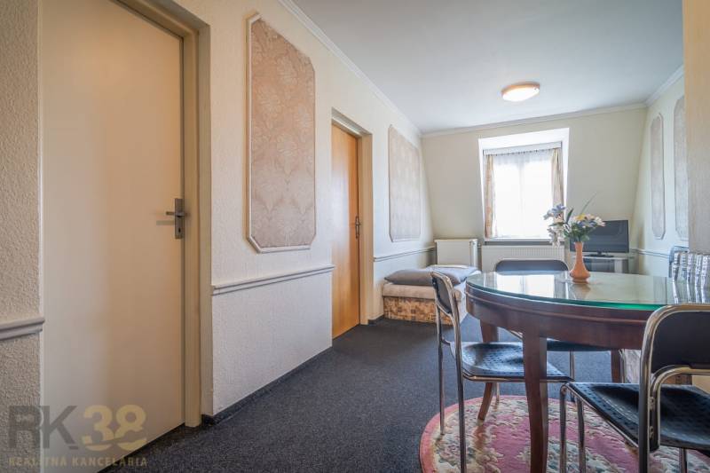 Szálloda és panzió belső tere kerek asztallal, szőnyeggel, TV-vel és díszített falakkal.