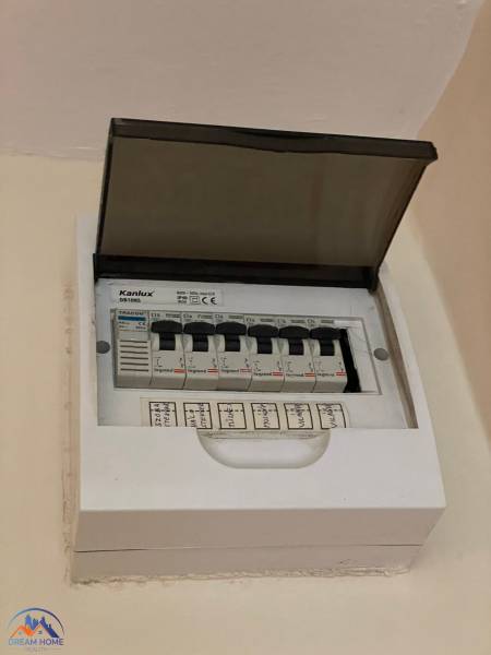 Elektromos elosztószekrény nyitott fedéllel és jelölt megszakítókkal egy egyszobás lakásban.