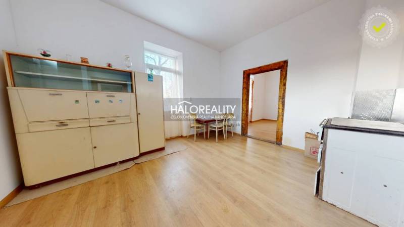 Családi ház belső tere fa dekorációjú padlóval, szekrénnyel és asztallal két székkel.