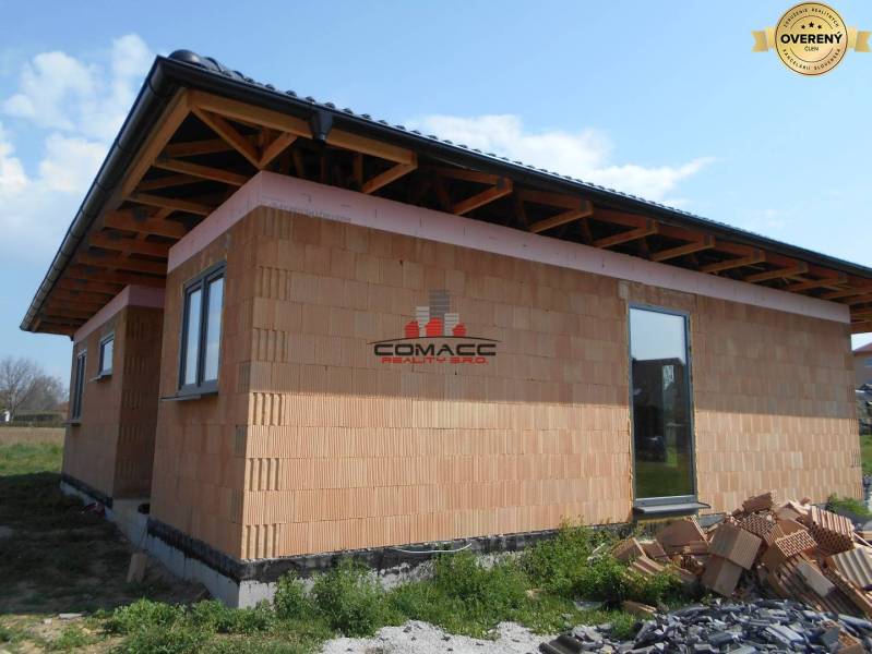 Családi ház Újvárosban, amely egy építés alatt álló épületet mutat tégla homlokzattal.