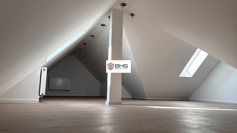 Tetőtéri helyiség 3 szobás lakásban ablakkal és fa dekor padlóval.