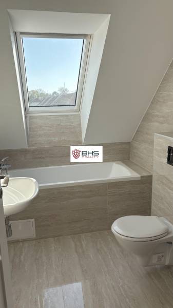 Fürdőszoba egy háromszobás lakásban káddal és tetőablakkal, fapadlóval.