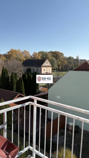 Kilátás egy háromszobás lakásból Tomášikovónál, amely kertekre és egy régi épületre néz.