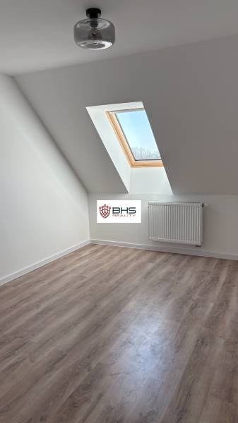 Tetőtéri szoba fa dekorációs padlóval és tetőablakkal egy háromszobás lakásban.