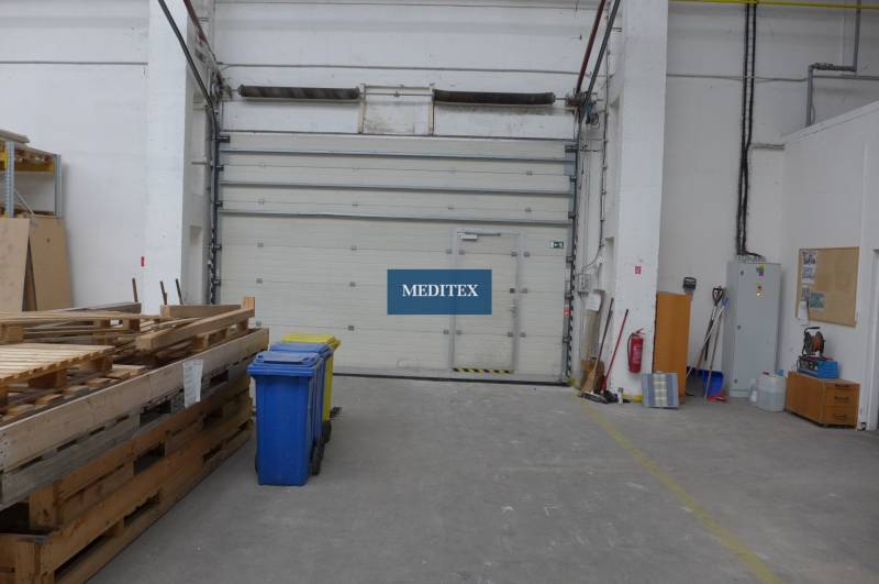 Raktárak és csarnokok raklapokkal, konténerekkel és nagy ajtókkal.