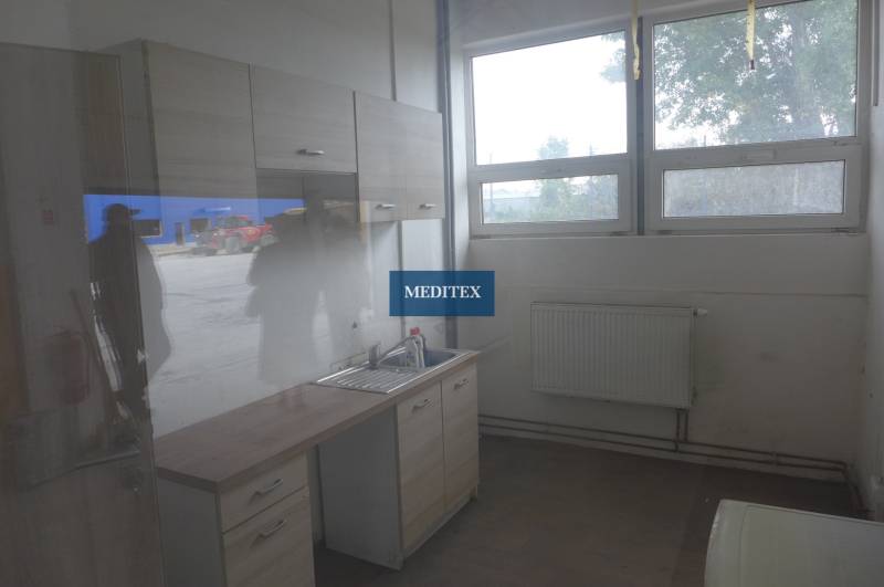 Konyhai rész szekrényekkel, mosogatóval és fa dekorációjú padlóval raktárak és csarnokok környezetében.