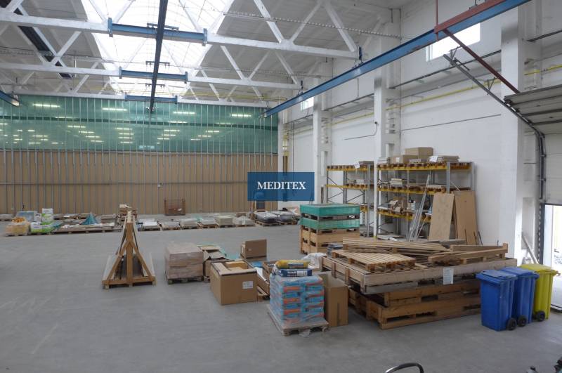 A raktárban raklapok vannak építőanyaggal és polcok táblákkal.