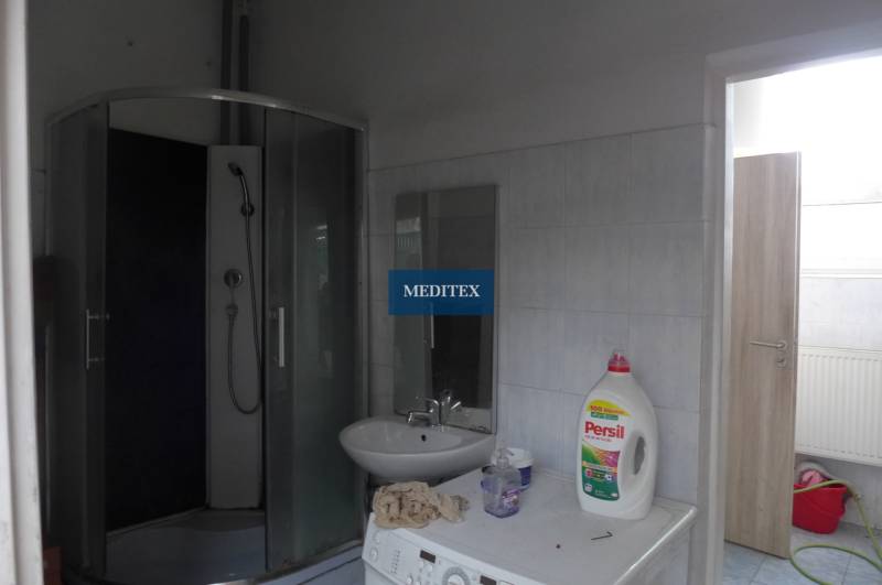 Fürdőszoba mosógéppel, zuhanyzóval és mosószerekkel.