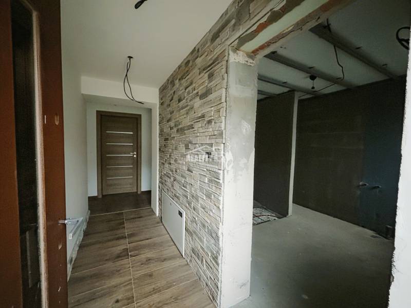 Folyosó kőhatású falburkolattal és fa hatású padlóval családi házban.