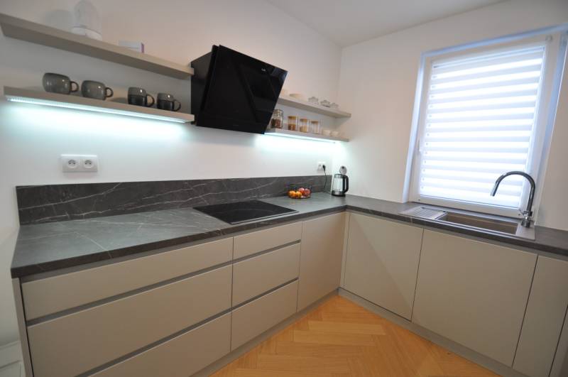 Konyha egy családi házban sötét munkalappal és fa dekorációjú padlóval.