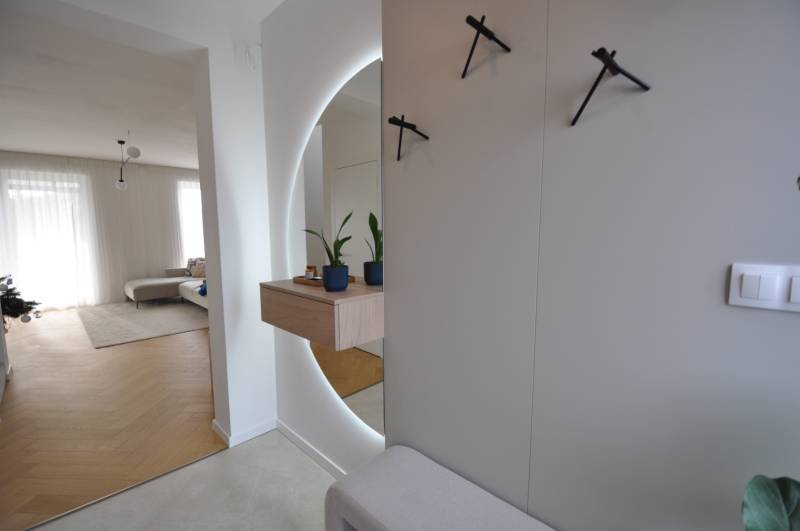 Családi ház belső tere fa mintázatú padlóval, tükörrel és szobanövényekkel.