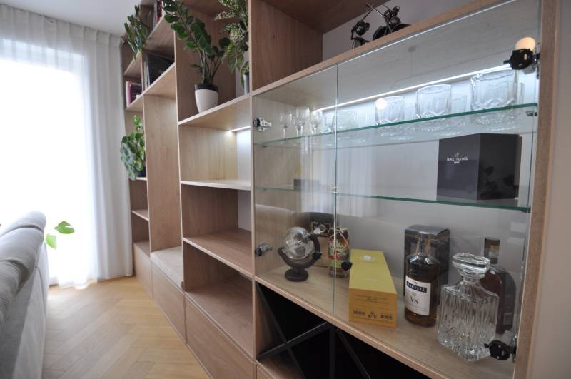 Családi ház belső tere szekrénnyel, üvegpolcokkal és fa dekoros padlóval.