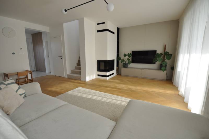 Nappali egy családi házban kandallóval és fa mintázatú padlóval.