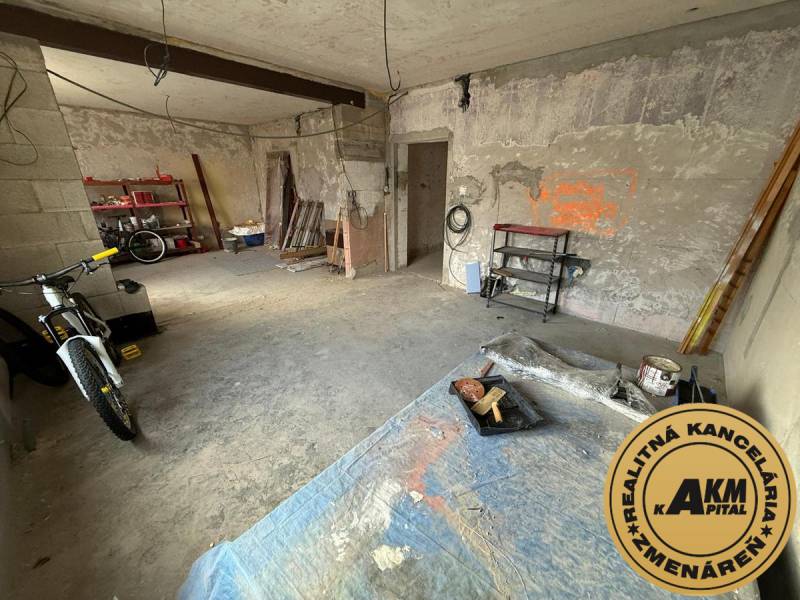 Befejezetlen szoba egy családi házban, kerékpárral és polcokkal különféle szerszámok számára.