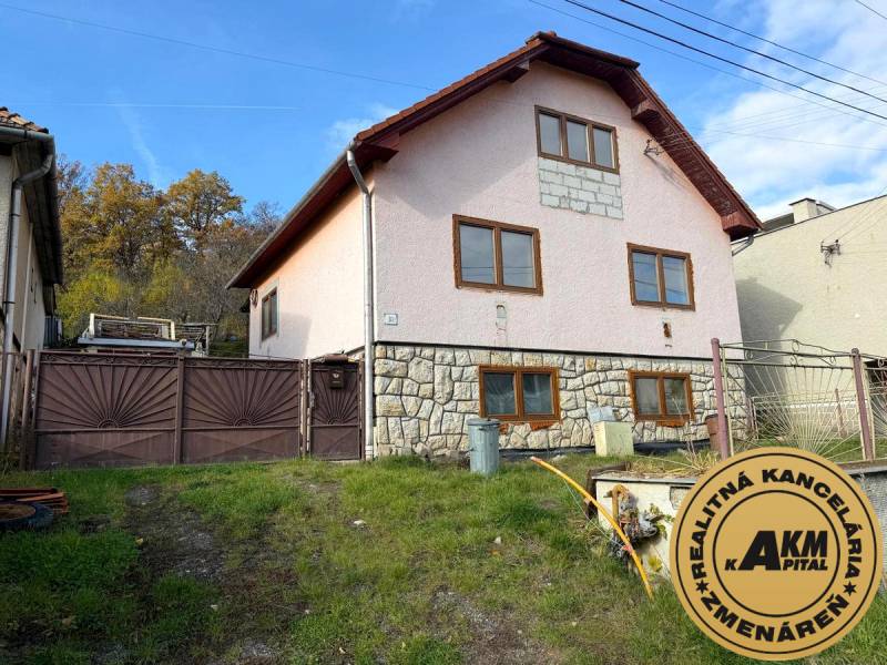 Családi ház Ókörmöcbányán lejtős kerttel és kő homlokzattal.